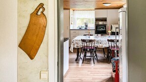 A kitchen with a dining table, chairs, and a hanging pot rack. - 2 bedroom awesome home in Gislatorp (Gislatorp)