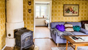 A cozy living room with a vintage stove, a sofa with colorful cushions, and a painting on the wall. - 2 bedroom awesome home in Gislatorp (Gislatorp)