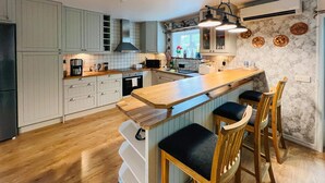 A modern kitchen with a central island, wooden bar stools, and a window with a view.