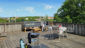 En træterrasse med sofa, stole og grill.