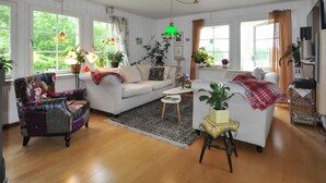 A cozy living room with a white sofa, patterned armchair, and a small table with a vase of flowers. - Amazing home in Kristinehamn with WiFi (Kristinehamn)
