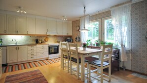 A kitchen with white cabinets, a dining table with chairs, and a window with curtains. - Amazing home in Kristinehamn with WiFi (Kristinehamn)