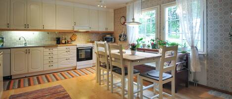 A kitchen with white cabinets, a dining table with chairs, and a window with curtains.