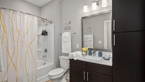 A modern bathroom with a bathtub, toilet, and vanity. - Studio/Self Check-In/30+Day Stays (Goose Creek)
