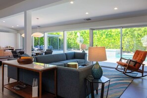 Ein modernes Wohnzimmer mit einer Eckcouch, einem Esstisch und einem Schaukelstuhl.