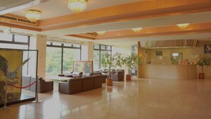 A spacious lobby with a reception desk, seating area, and large windows offering a view of greenery. - Inawashiro Kanko Hotel  (Inawashiro)