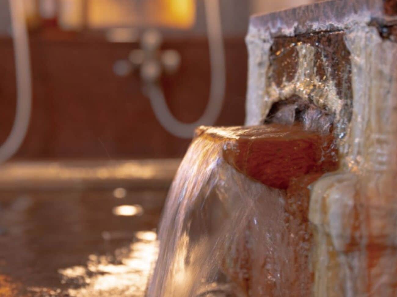 A close-up of a water spout with a metal pipe and a valve in the background.