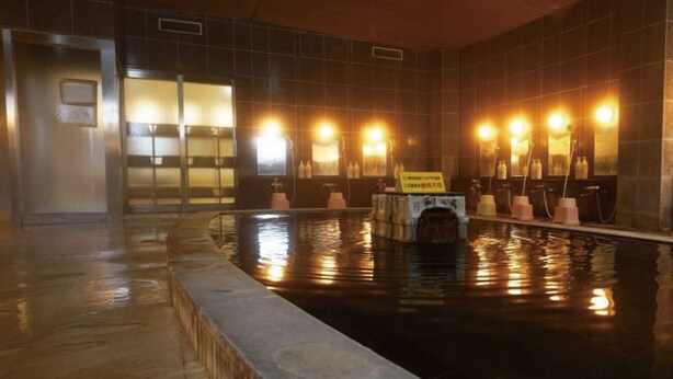 A swimming pool with a wooden ceiling and tiled walls, surrounded by benches and illuminated by wall-mounted lights. - Inawashiro Kanko Hotel  (Inawashiro)