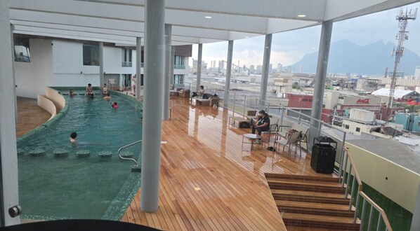 Zona de piscina con vista a la ciudad y montañas al fondo.