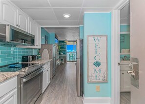 A kitchen with white cabinets, a microwave, and a toaster. There is a 'WELCOME' sign on the wall.