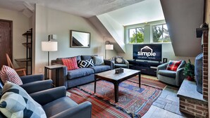 A modern living room with a sofa, chairs, a coffee table, and a TV displaying 'Simple Vacation Rentals'.
