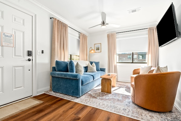 Una sala de estar moderna con un sofá azul, una mesa de centro de madera y un sillón marrón.