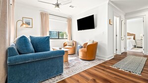 Un salon moderne avec un canapé bleu, un fauteuil rond orange et un téléviseur à écran plat fixé au mur.