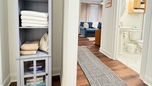 Un couloir avec une étagère grise, un tapis à motifs et un canapé bleu en arrière-plan.