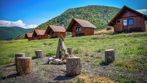 Une rangée de cabanes en bois aux toits en pente, se dressant sur un fond de colline verdoyante.