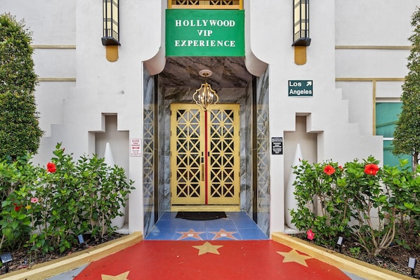A building entrance with a sign reading "Hollywood VIP Experience" and a directional sign to Los Angeles.