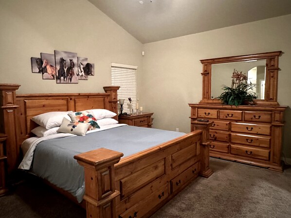 Ein Schlafzimmer mit einem hölzernen Bett, einem Schminktisch, einem Spiegel und Wandbildern.