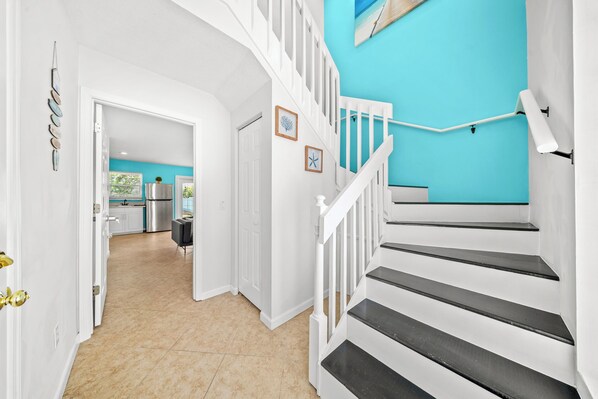 A staircase with white railings and black steps leading to a room with a turquoise wall.