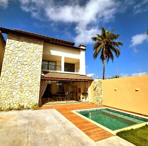 A modern two-story house with a stone facade, a swimming pool, and a palm tree in the background. - Refúgio Praiano do Atalaia (Salinópolis)