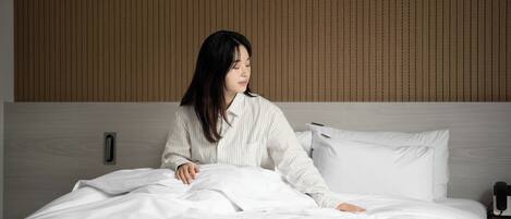 A hotel room with a bed, a bedside table, and a wall with vertical lines.