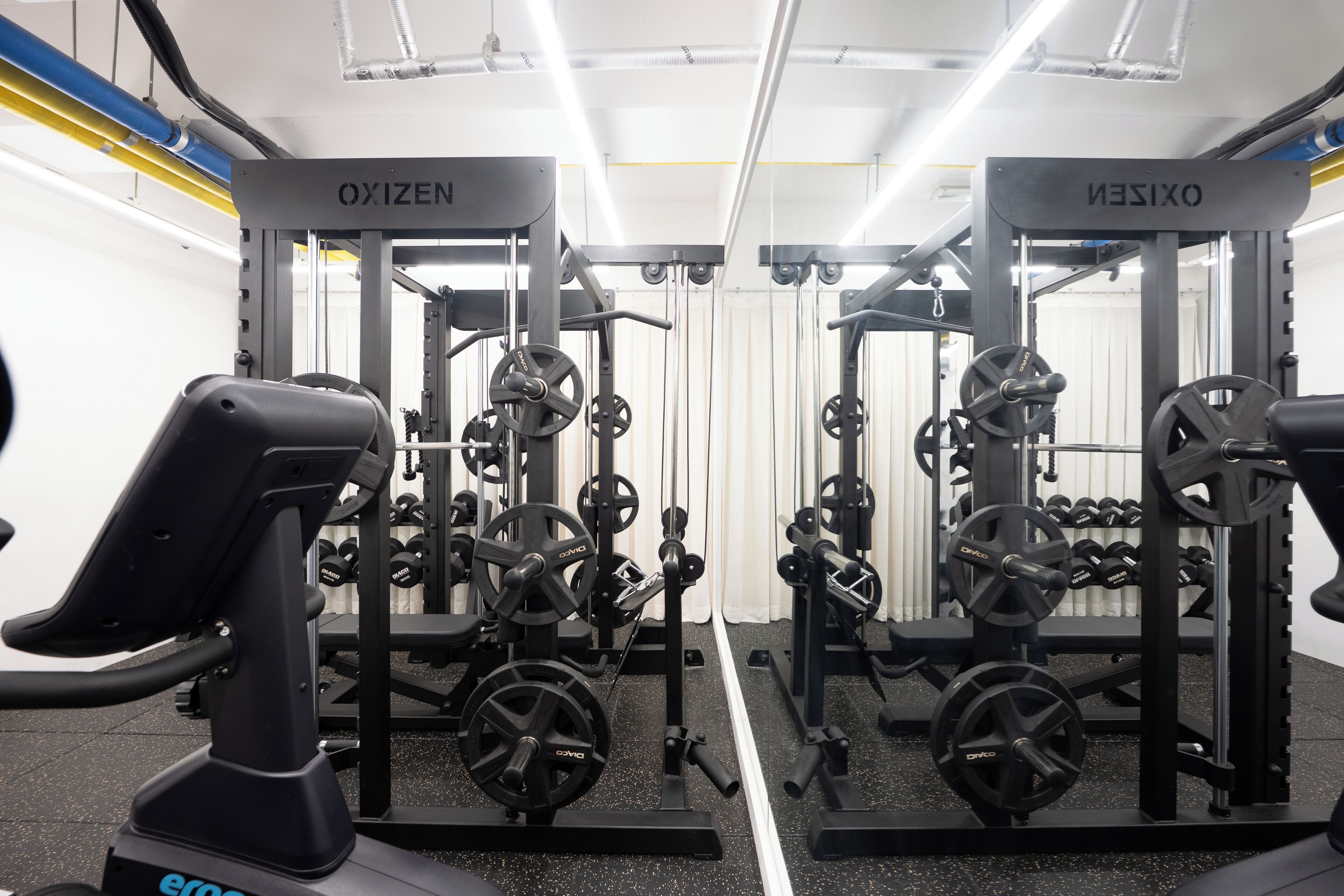 A gym with weightlifting equipment, benches, and dumbbells.