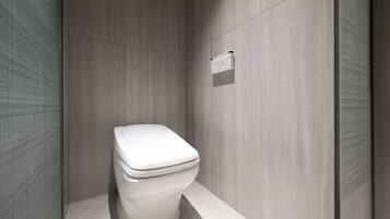 Un baño moderno con inodoro blanco, panel de control en la pared y suelo de baldosas.