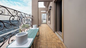 Ein Balkon mit einem gemusterten Boden, einem Tisch und einem weißen Gegenstand sowie einem Geländer.