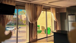 A modern living room with a large sliding glass door leading to an outdoor area. - 3-bedroom Luxury Villa with Private Pool (Taht Eddoum)