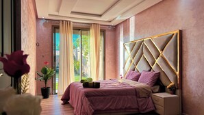 A bedroom with a large bed, a nightstand, and a potted plant. - 3-bedroom Luxury Villa with Private Pool (Taht Eddoum)