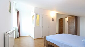 A bedroom with a bed, a radiator, a door, and a light fixture.