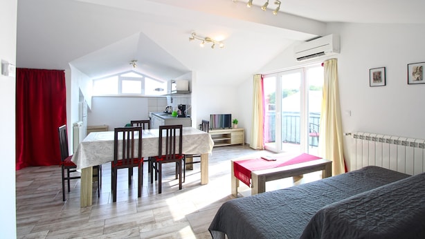 A spacious room with a dining area, a bed, and a balcony with a view.