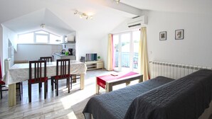 A compact living space with a kitchenette, a dining area, a bedroom with a bed, and a sliding glass door leading to an outdoor area.
