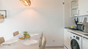 Uma cozinha moderna com máquina de lavar embutida, uma mesa de jantar posta com pratos e copos, e um lustre.