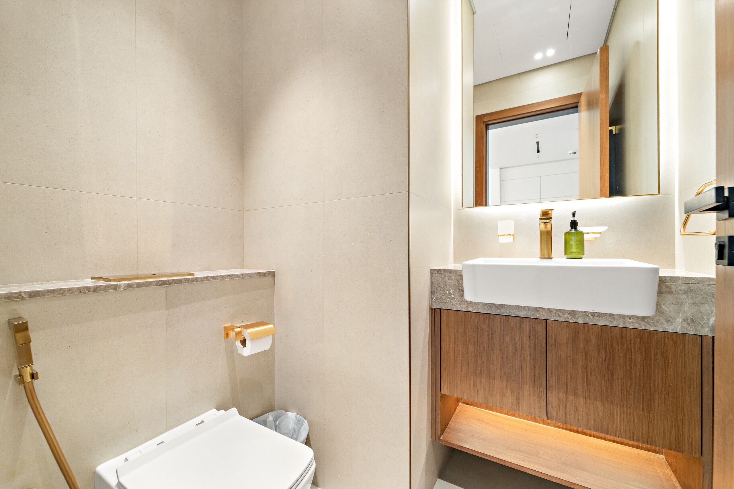 Un baño moderno con un lavabo blanco, tocador de madera y un espejo sobre el lavabo.