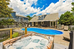 A backyard with a swimming pool, hot tub, and outdoor seating area.