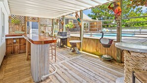 An outdoor patio with a pool, wooden deck, bar area, and a statue.