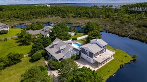 A large house with a swimming pool, surrounded by water and greenery.