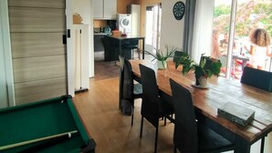 A dining area with a pool table, a ceiling fan, and a view of the outside.