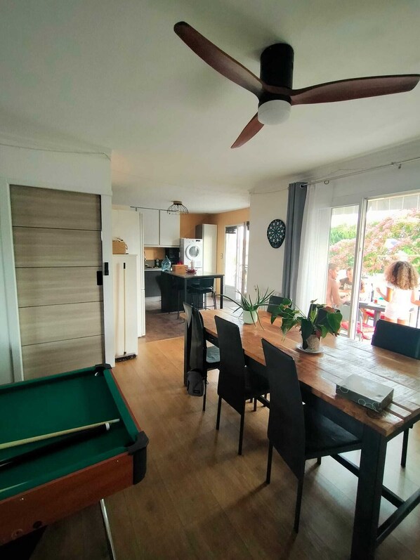 A dining area with a pool table, a ceiling fan, and a view of the outside.