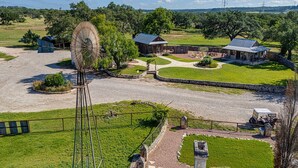 Una propiedad rural con un molino, edificios de piedra y un césped bien cuidado.