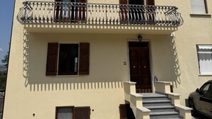Un bâtiment à deux étages doté d’un balcon, d’une porte et d’un escalier menant à l’entrée.