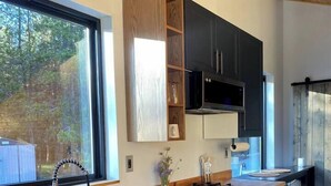 Une cuisine moderne dotée d’une grande fenêtre, de meubles de rangement aux couleurs sombres et d’un plan de travail en bois.