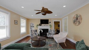 A living room with a fireplace, a ceiling fan, and a green sofa. - Pet-Friendly Home by Trail & Base (Columbus)