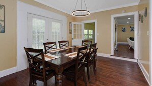 A dining room with a wooden table and chairs, a hanging light fixture, and a door leading to another room. - Pet-Friendly Home by Trail & Base (Columbus)