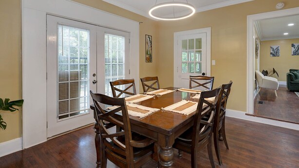 A dining room with a wooden table and chairs, white doors with blinds, and a ceiling light fixture. - Pet-Friendly Home by Trail & Base (Columbus)