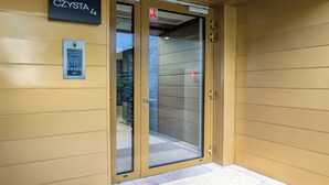 A modern elevator entrance with a glass door, a sign indicating the floor number, and a fire alarm sign above the door. - Czysta Chic Harmony Studio (Wrocław)