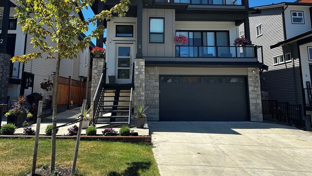 A modern two-story residential building with a garage, a balcony with potted plants, and a well-maintained lawn. - Kam Residence  (Chilliwack)