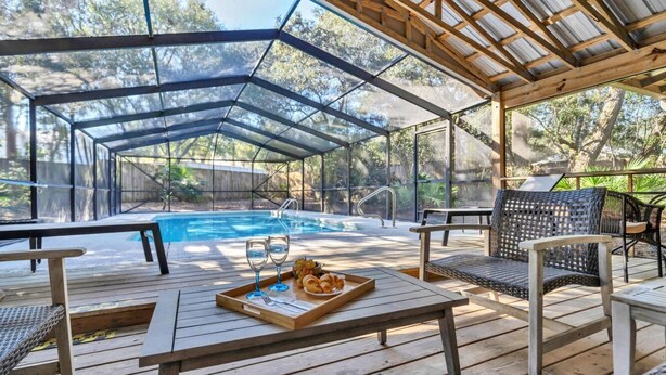 Un espace extérieur avec piscine, une terrasse en bois, des chaises longues et une table sur laquelle se trouve un plateau de nourriture et de boissons.
