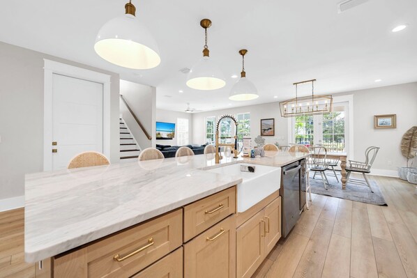 A modern kitchen with a marble countertop, wooden cabinets, and pendant lighting.