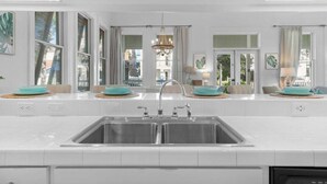 Une cuisine moderne avec des meubles blancs, un grand évier double et un lustre.